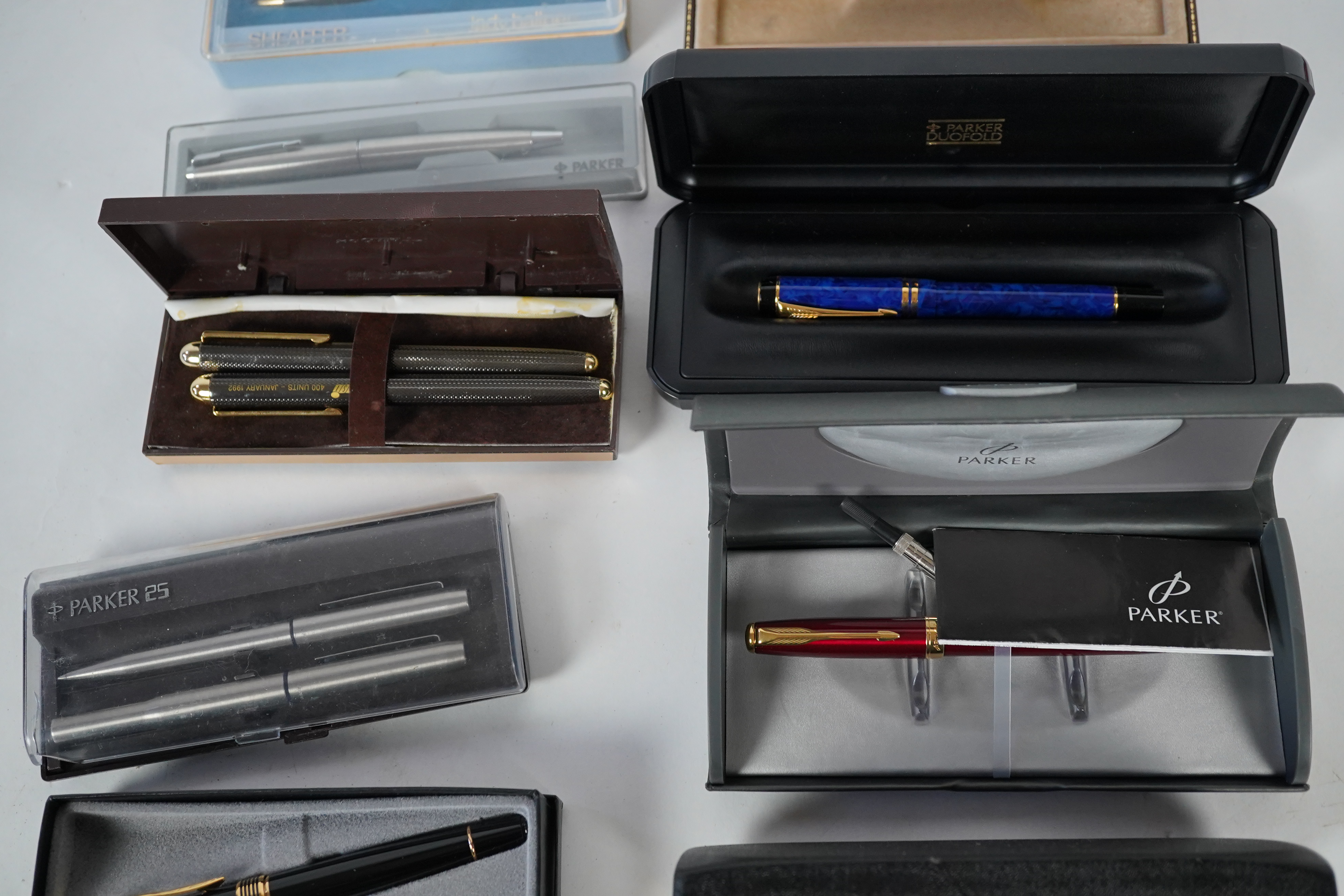 A cased Parker duofold ballpoint pen, a cased Parker Sonnet lacquer ruby red fountain pen, a Dunhill gold plated fountain pen and various fountain pens and ballpoint pens including Parker, Sheaffer, Quill, etc.